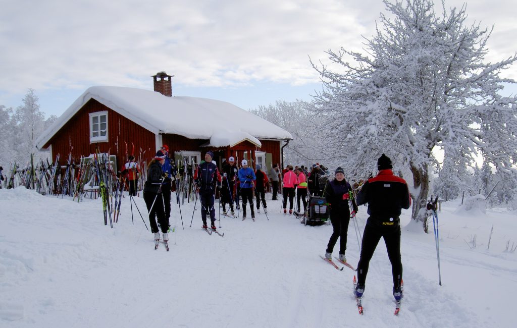 Många skidor vid stugan i snö